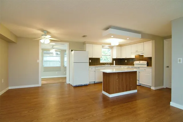 a kitchen with stainless steel appliances wooden floor and a refrigerator