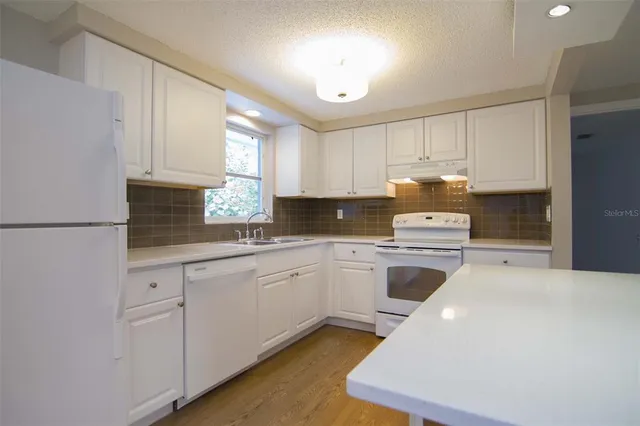 a kitchen with granite countertop white cabinets and white appliances
