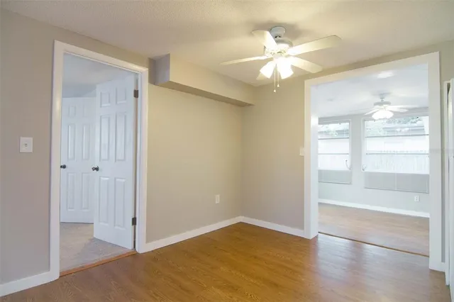an empty room with wooden floor fan and windows