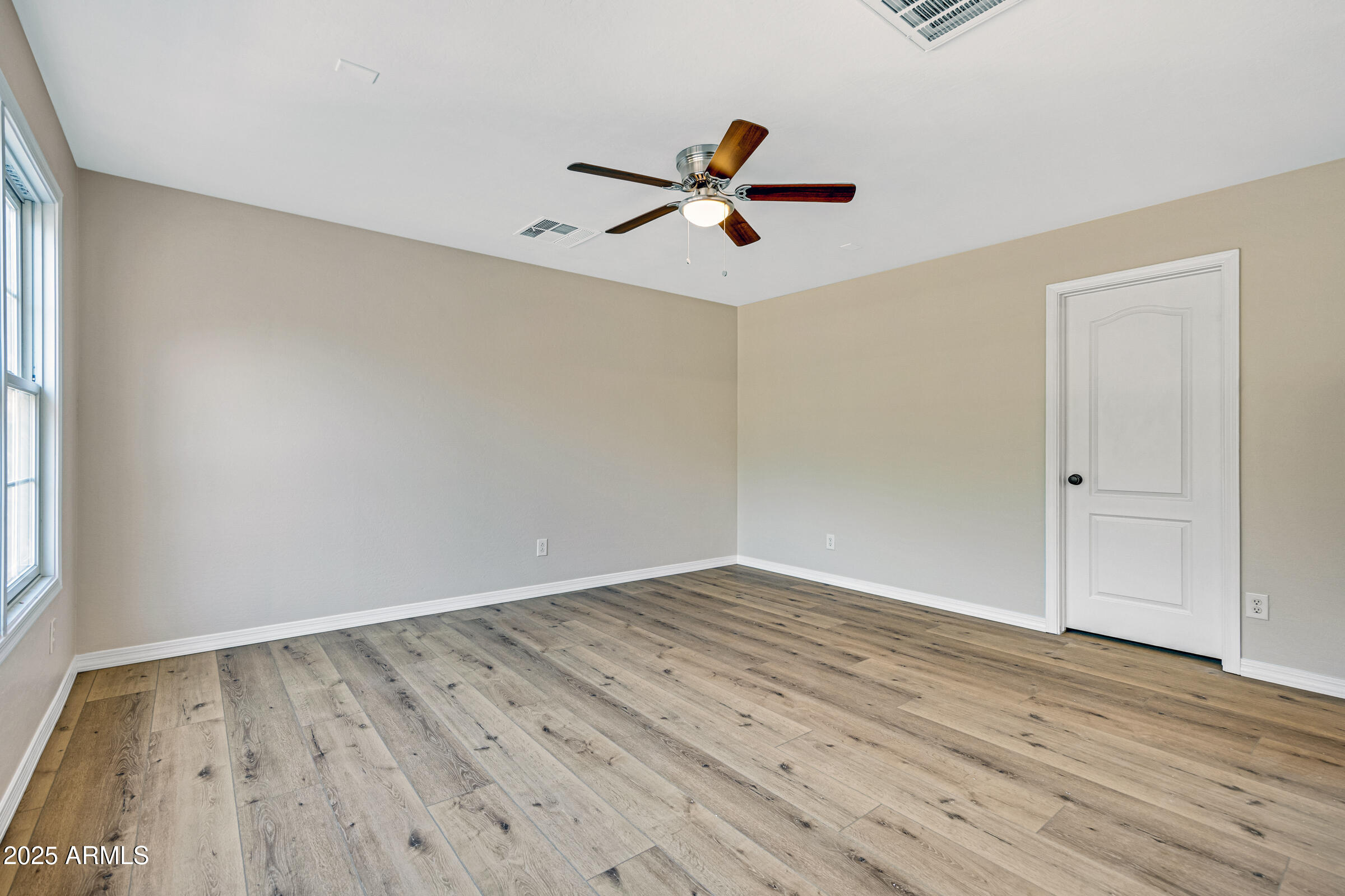 2315 East Pecan Road Phoenix, AZ 85040 - Photo 29 of 36 an empty room with wooden floor a ceiling fan and windows