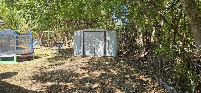 a view of a backyard with large trees and wooden fence