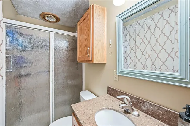 a bathroom with a granite countertop sink mirror vanity and toilet