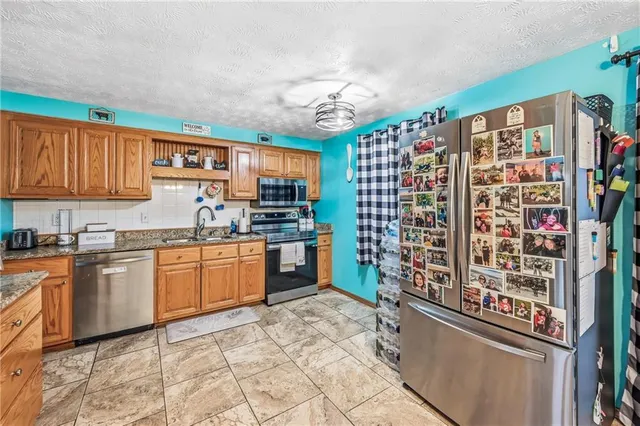 a kitchen with stainless steel appliances granite countertop a refrigerator and a stove top oven