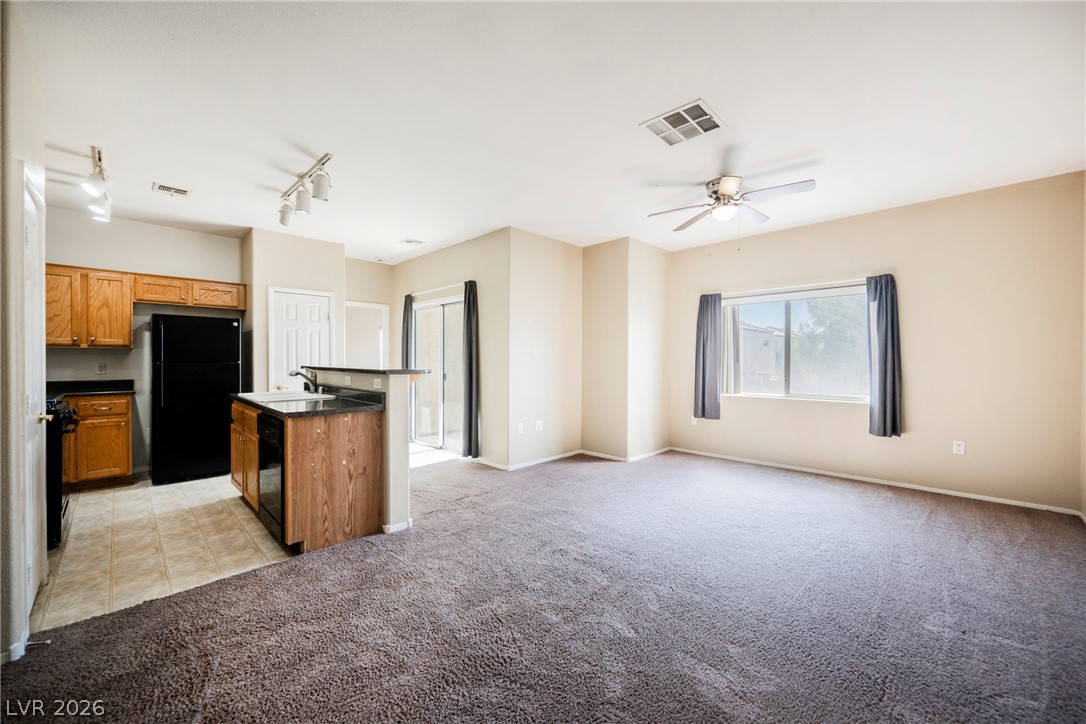 6320 Snap Ridge Street, Unit 201 North Las Vegas, NV 89081 - Photo 1 of 56 An inviting open-concept layout connects a functional kitchen with a comfortable living space, featuring a bright window and a ceiling fan.
