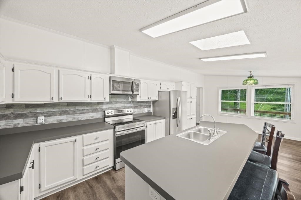 938 Riley Creek Road Whitleyville, TN 38588 - Photo 10 of 40 a kitchen with stainless steel appliances granite countertop a stove a sink dishwasher a microwave oven and white cabinets with wooden floor