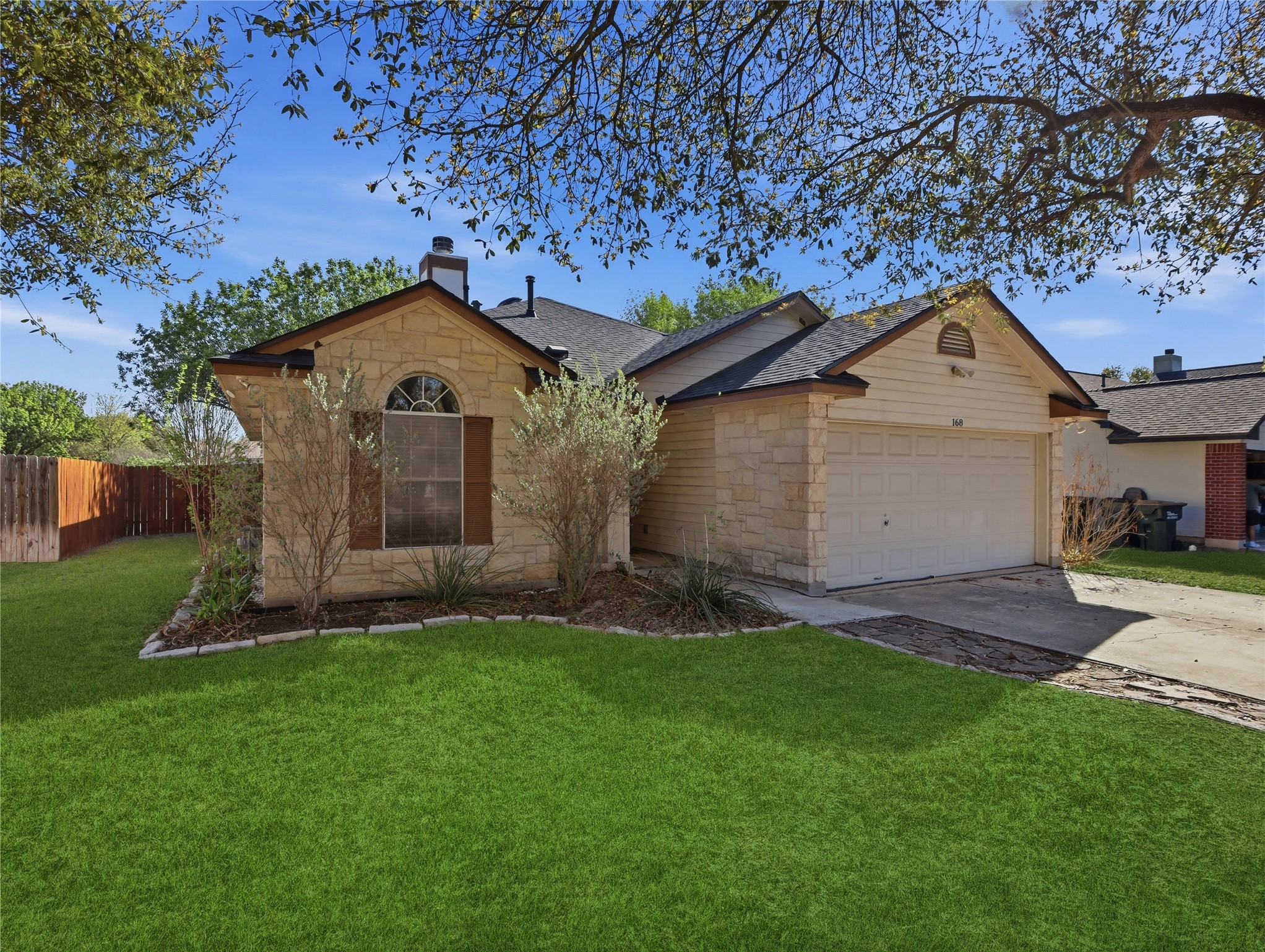 Single story home with stone siding, concrete driveway, a chimney, a garage, and roof with shingles