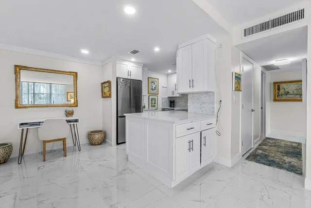 a kitchen with white cabinets and refrigerator