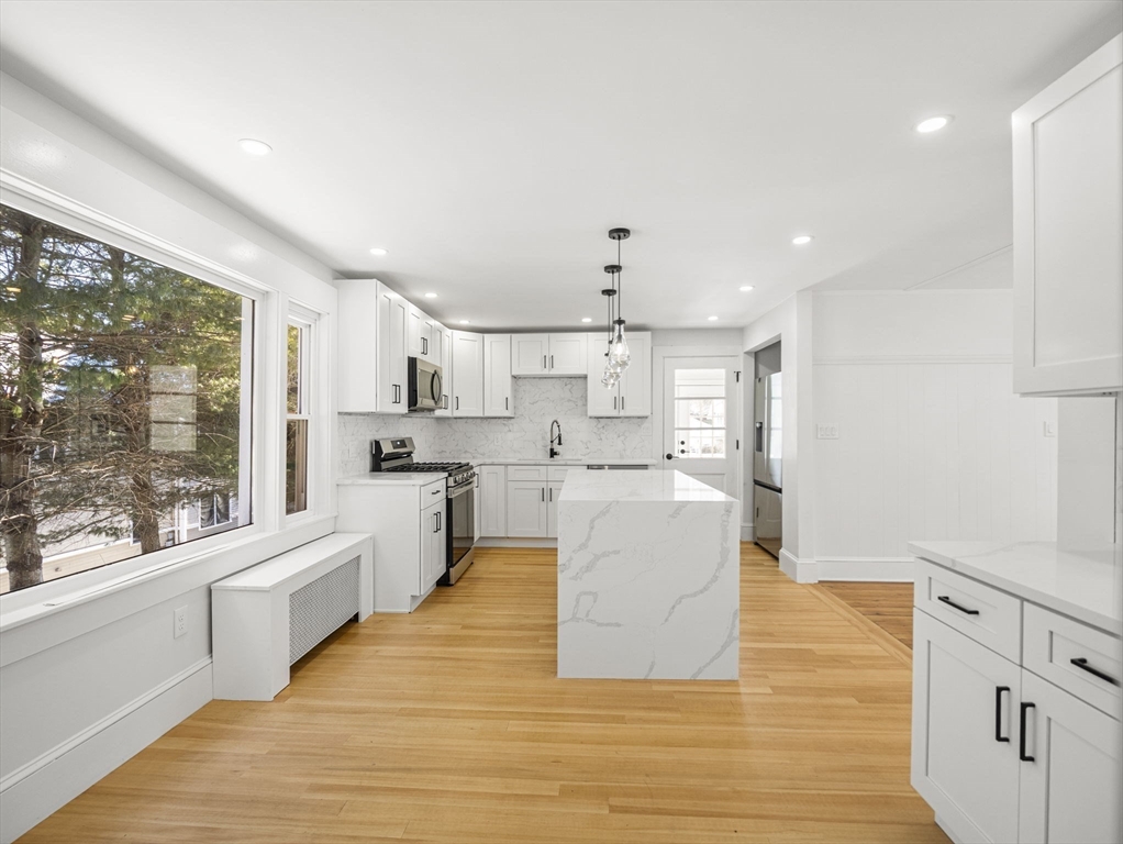 224 Pelham Street Methuen, MA 01844 - Photo 11 of 40 a large white kitchen with kitchen island a large window a sink and a stove
