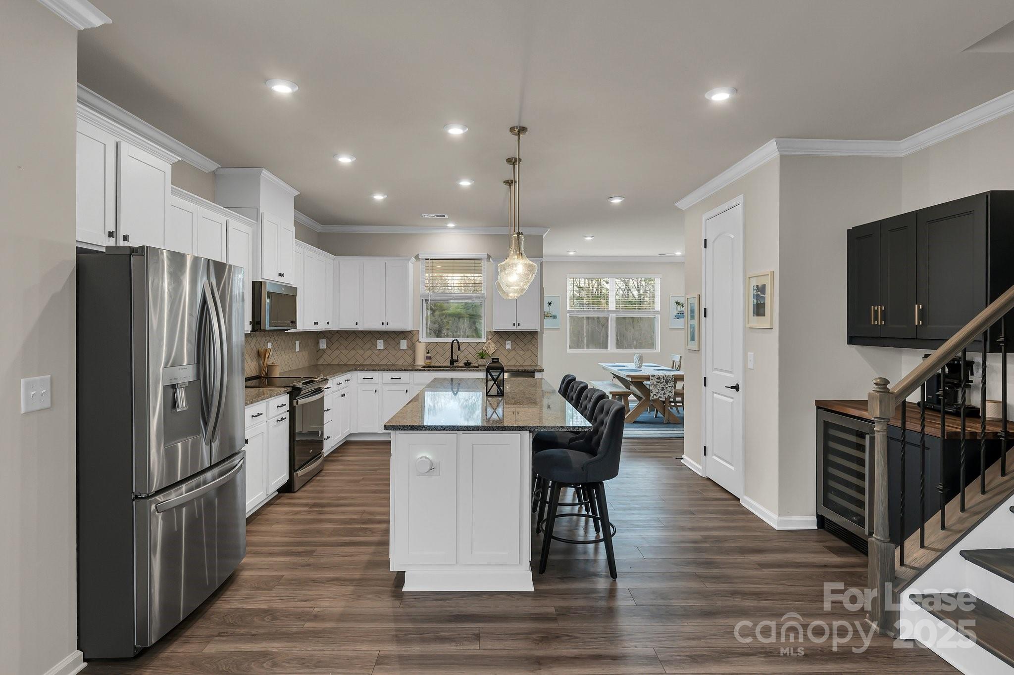16764 Summers Walk Boulevard Davidson, NC 28036 - Photo 16 of 26 a kitchen with stainless steel appliances kitchen island granite countertop a refrigerator a stove a sink a dining table and chairs with wooden floor