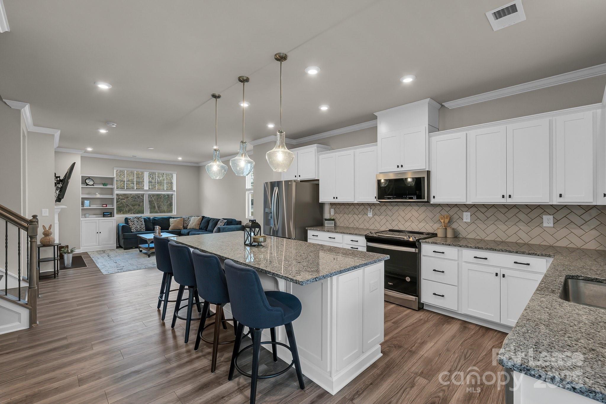 16764 Summers Walk Boulevard Davidson, NC 28036 - Photo 9 of 26 a large kitchen with kitchen island a dining table chairs and white cabinets