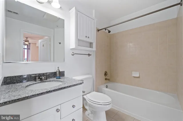 a bathroom with a granite countertop sink a toilet and shower