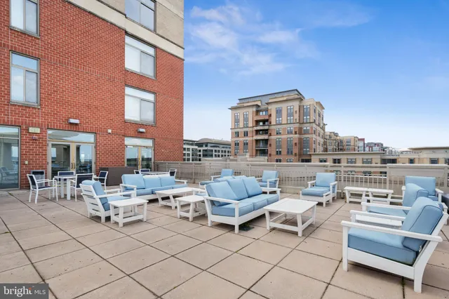 a view of roof deck with couches and potted plants