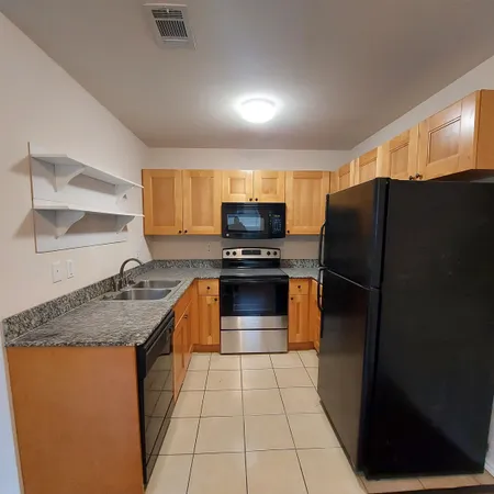 a kitchen with granite countertop a refrigerator and a sink