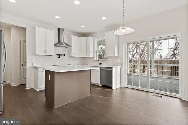 a kitchen with stainless steel appliances granite countertop a stove a sink and white cabinets with wooden floor next to windows