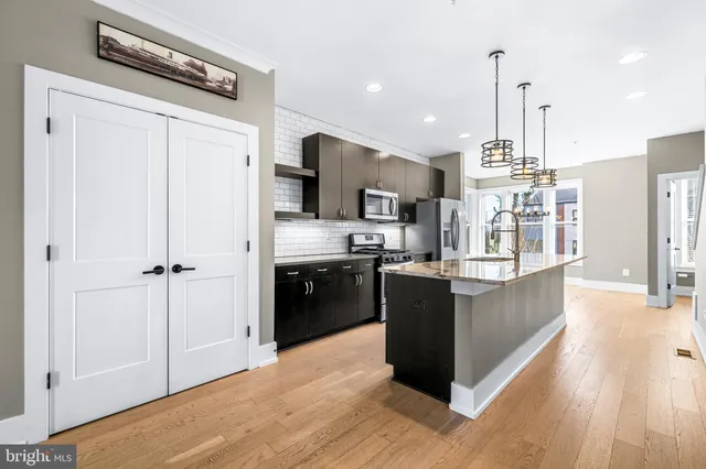 a large kitchen with a center island wooden floor stainless steel appliances and windows