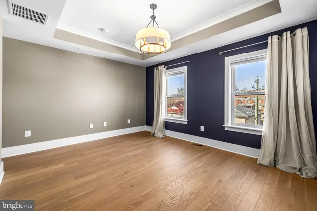 a view of an empty room with a window and wooden floor