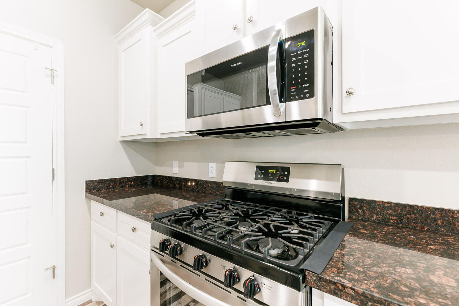 6956 12th Street Lubbock, TX 79416 - Photo 12 of 43 a kitchen with granite countertop a stove a microwave a sink and cabinets