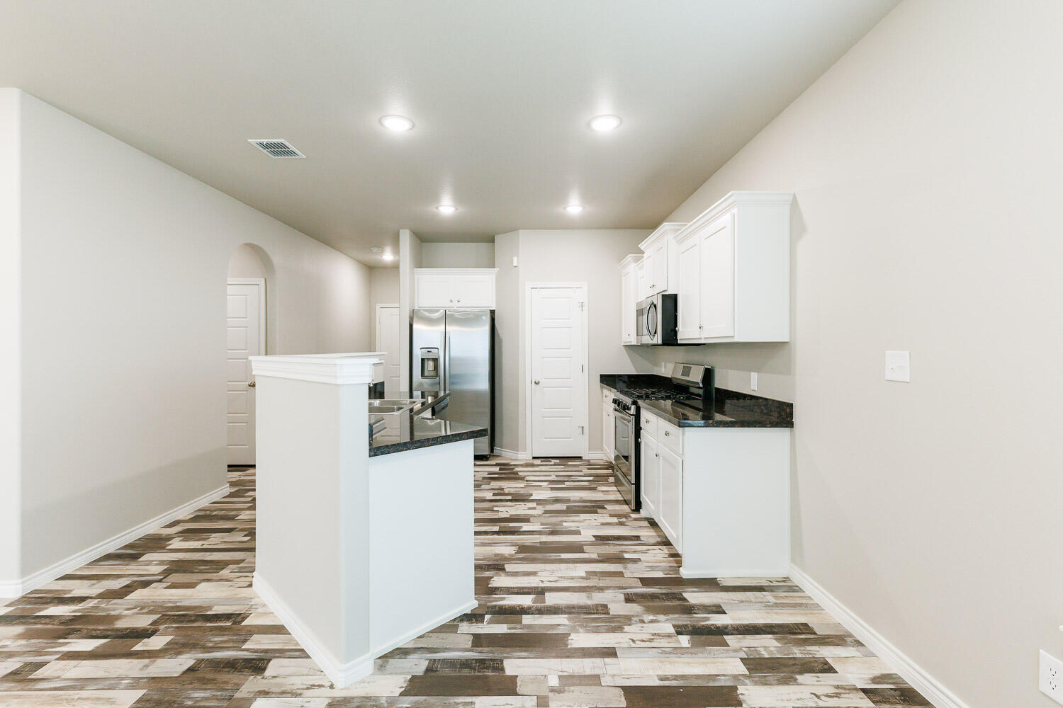 6956 12th Street Lubbock, TX 79416 - Photo 6 of 43 a kitchen with stainless steel appliances kitchen island granite countertop a refrigerator and a stove top oven