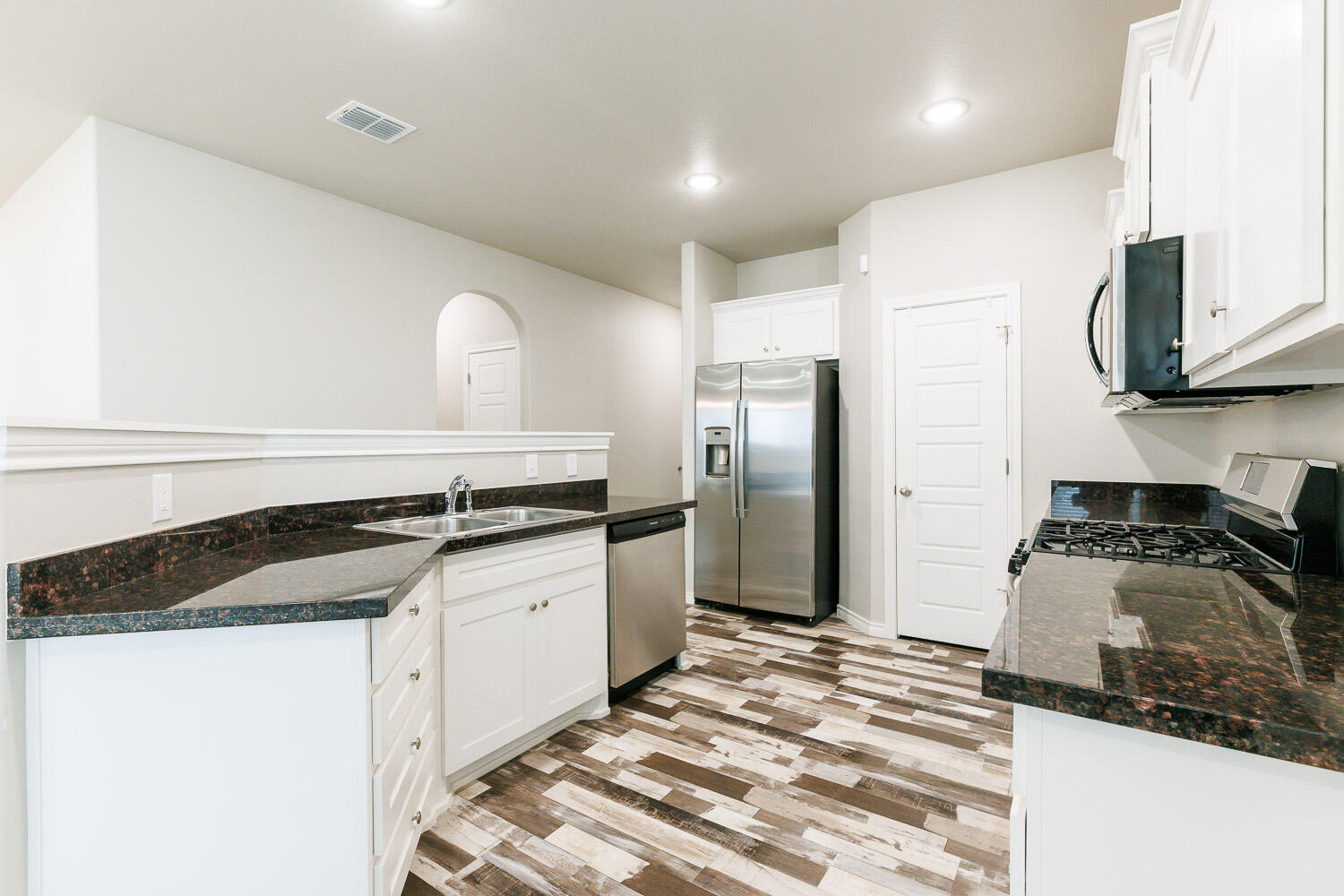 6956 12th Street Lubbock, TX 79416 - Photo 8 of 43 a kitchen with granite countertop a sink stainless steel appliances and white cabinets