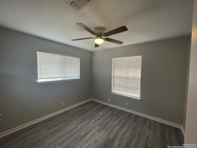 a view of empty room with wooden floor and fan