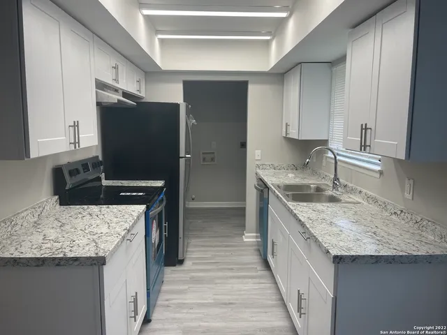 a kitchen with granite countertop a sink stove and refrigerator