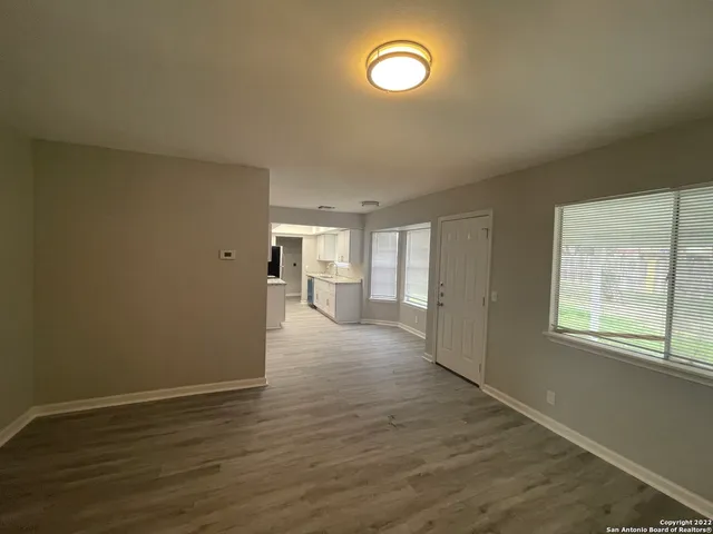 an empty room with wooden floor and windows
