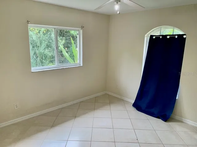 en empty room with windows and ceiling fan