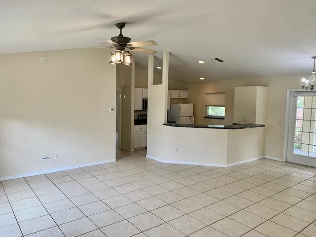 an empty room with kitchen view and a window