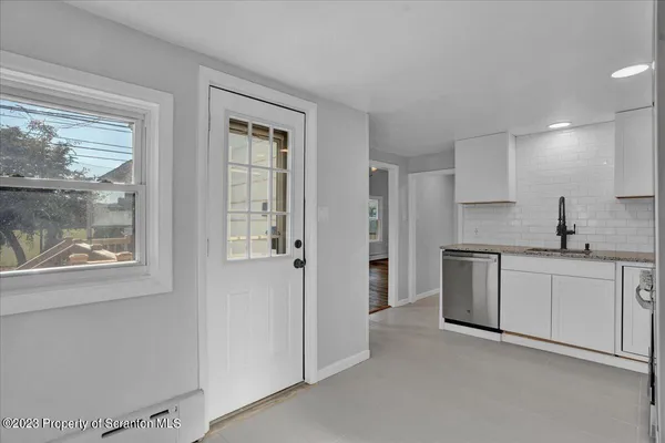 a kitchen with white cabinets and window