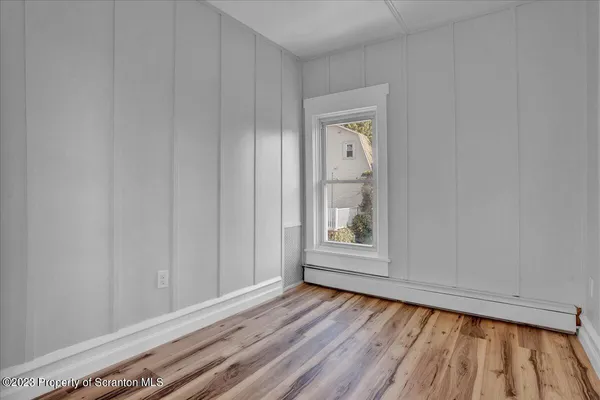 a view of an empty room with wooden floor and a window