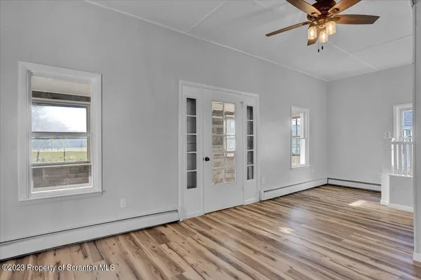 a view of an empty room with window and wooden floor