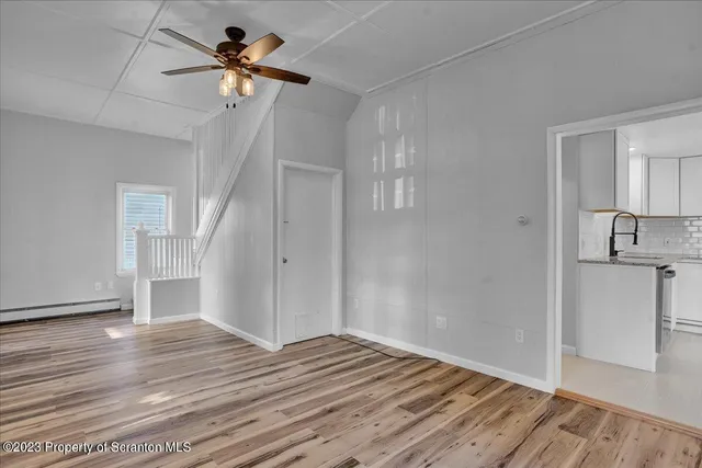 a view of a livingroom with wooden floor and a ceiling fan