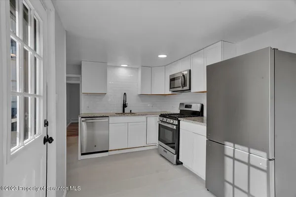a kitchen with cabinets stainless steel appliances and a refrigerator