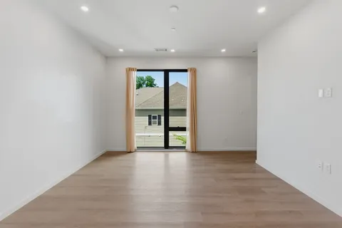 a view of an empty room with a window and wooden floor