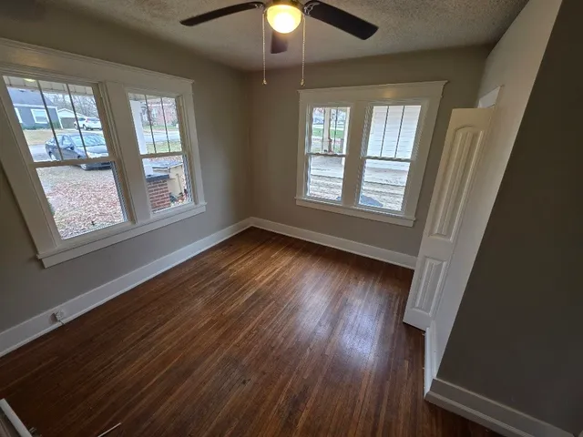 a view of an empty room with wooden floor and a window