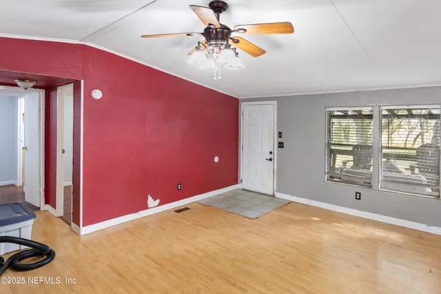 a view of a livingroom with a chandelier fan and windows