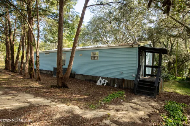 a view of a house with backyard and trees