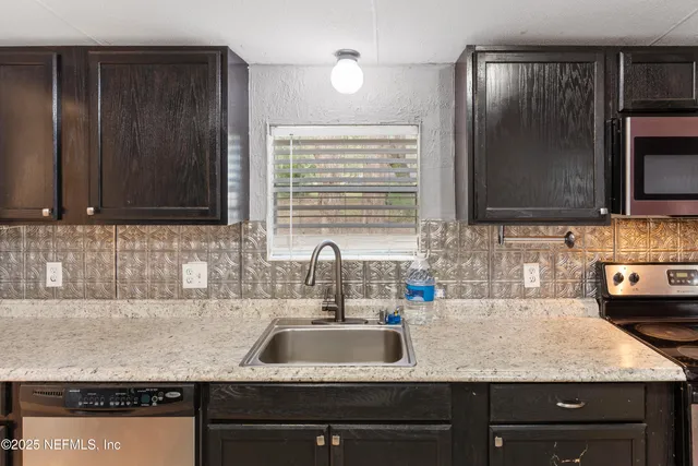 a kitchen with granite countertop stainless steel appliances a sink stove and microwave