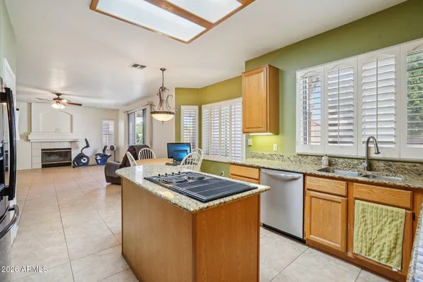 a kitchen with stainless steel appliances granite countertop a stove a sink dishwasher and a refrigerator with wooden cabinets