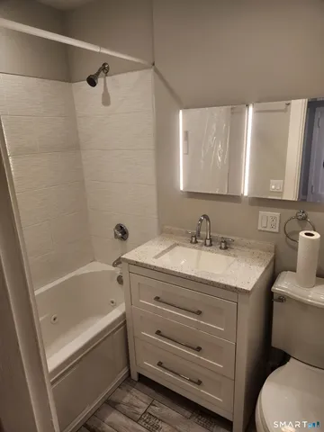 a bathroom with a granite countertop sink a toilet and bathtub
