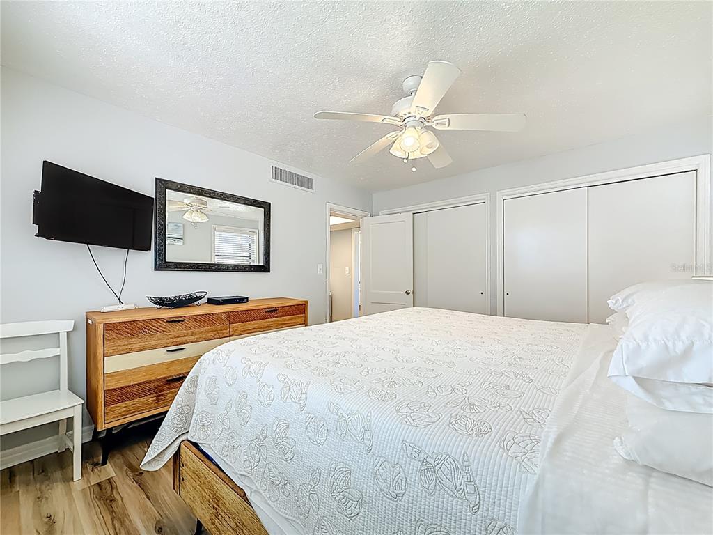 6700 Sunset Way, Unit 604 St. Pete Beach, FL 33706 - Photo 19 of 27 a bedroom with a bed and a flat screen tv