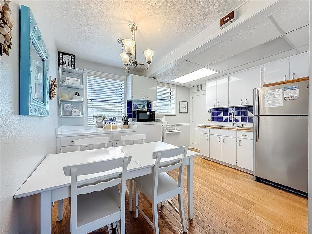6700 Sunset Way, Unit 604 St. Pete Beach, FL 33706 - Photo 9 of 27 a kitchen with a dining table chairs refrigerator and cabinets