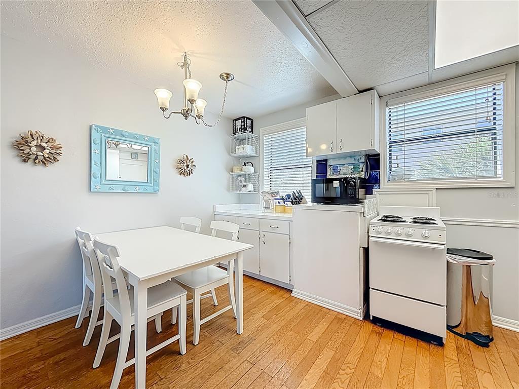 6700 Sunset Way, Unit 604 St. Pete Beach, FL 33706 - Photo 10 of 27 a kitchen with a table chairs a stove a dining table and chairs
