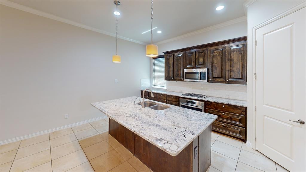 14712 Spitfire Trail Fort Worth, TX 76262 - Photo 6 of 25 Kitchen featuring a large island with a double basin sink, stainless steel appliances, dark wood-finish cabinetry, and recessed lighting