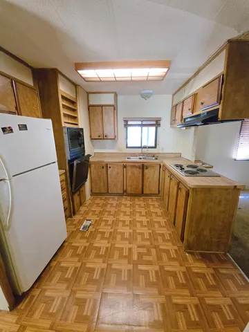 a large white kitchen with sink a refrigerator and a stove