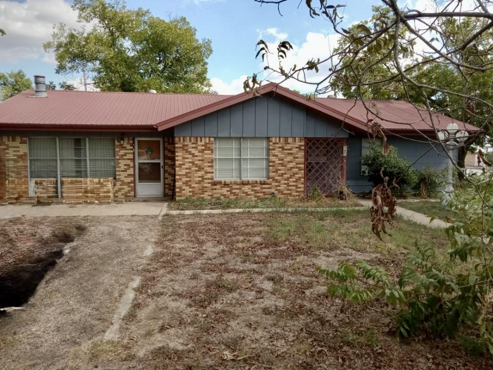 709 West 11th Street Elgin, TX 78621 - Photo 2 of 12 Ranch-style home featuring brick siding, board and batten siding, and a metal roof