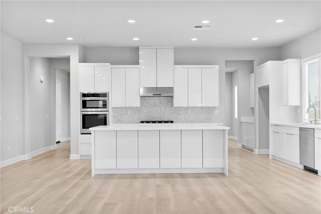 12925 Davona Dale Road Apple Valley, CA 92308 - Photo 17 of 44 a large white kitchen with kitchen island a sink a refrigerator and white cabinets