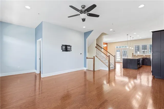 a view of an empty room with wooden floor and a ceiling fan