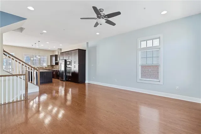 a view of an empty room with wooden floor and a ceiling fan
