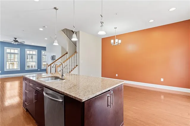 a kitchen with stainless steel appliances granite countertop a sink and a wooden floor